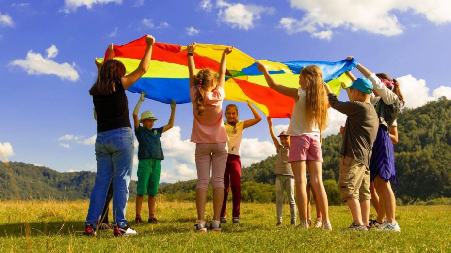 Kinder stehen auf einem Feld in einem Kreis und halten eine Fahne über ihren Köpfen.