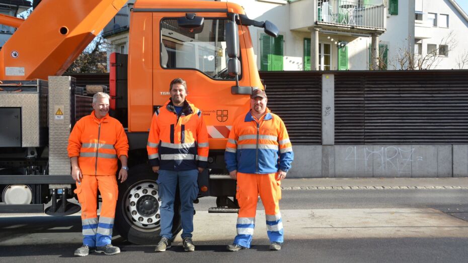 Das Team der Strassenbeleuchtung vor dem orangen Lastwagen.