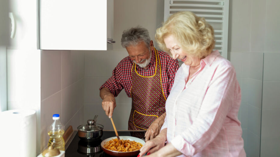 Ein älterer Mann und eine ältere Frau kochen gemeinsam eine Mahlzeit in ihrer Küche.