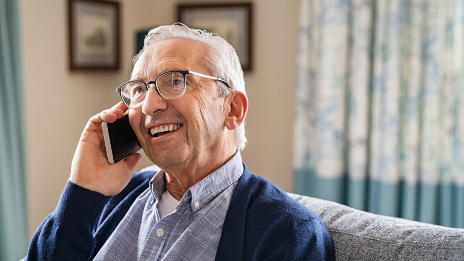 Ein Senior hält ein Mobiltelefon ans Ohr und telefoniert.